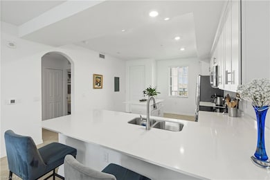 Kitchen with white cabinets, a peninsula, arched walkways, a kitchen bar, and recessed lighting