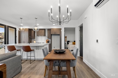 Dining space featuring light wood-style flooring, a chandelier, a wall unit AC, and recessed lighting