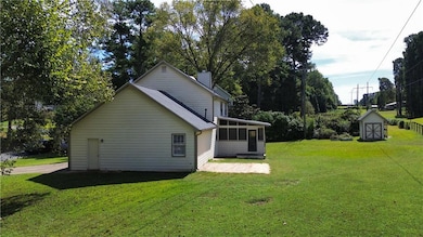 View of side of home featuring a sunroom, a lawn, a chimney, and view of wooded area