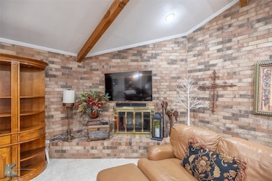 Living room with crown molding, carpet flooring, brick wall, and a fireplace