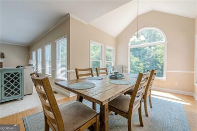 Dining area featuring light wood finished floors, a chandelier, vaulted ceiling, and baseboards
