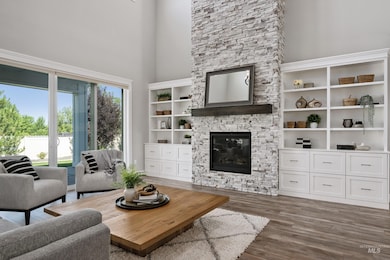 Living room with a towering ceiling, a fireplace, and wood finished floors