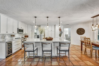 Chef's Kitchen Cafe appliances and under counter wine fridge. Statement piece island with plenty of seating and tons of storage. Friendly living Saltillo tile floor.