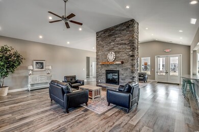 Living room with a stone fireplace, ceiling fan, f