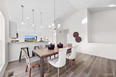 Dining space with high vaulted ceiling, a chandelier, light wood finished floors, and recessed lighting