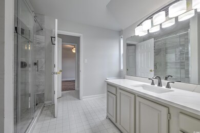 Bathroom with tile patterned floors, vanity, and a shower with door