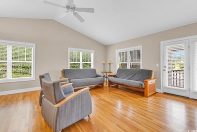 Living area featuring light wood-style floors, vaulted ceiling, and ceiling fan