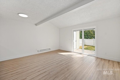 Empty room featuring beamed ceiling, a textured ceiling, light wood-type flooring, and a baseboard radiator