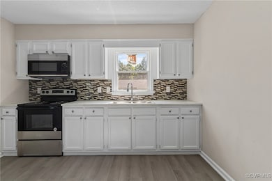 Kitchen featuring white cabinets, light wood-type