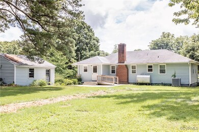 Rear view of property featuring oil tank, a chimney, and a lawn