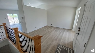 Additional living space featuring light wood-type flooring and lofted ceiling