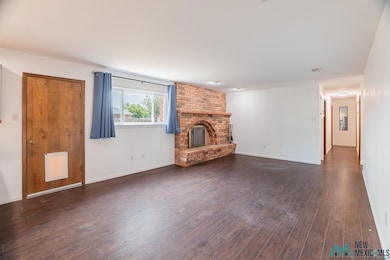 Unfurnished living room with a brick fireplace and dark wood-style flooring