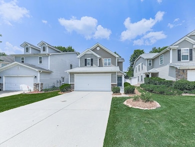 View of front of property featuring stone siding, concrete driveway, a front lawn, and a residential view