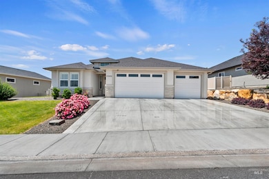 Prairie-style house with stucco siding, an attached garage, driveway, and stone siding