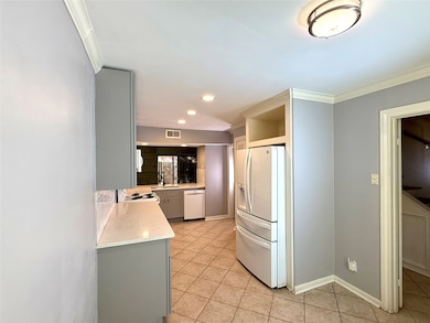 Bright kitchen with appliances, including fridge, ample counter space, and soft lighting. Perfect for cooking and entertaining.