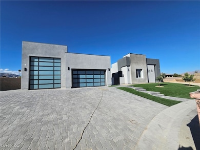 Contemporary home featuring a glass garage door, stucco siding, decorative driveway, and a front lawn.