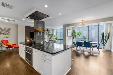 Kitchen featuring oven, black electric stovetop, dark countertops, dark wood-type flooring, and recessed lighting