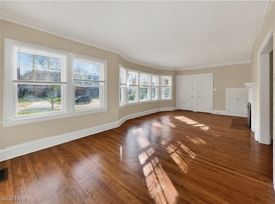 Unfurnished living room with crown molding and wood finished floors