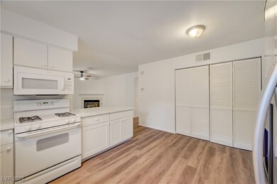 Kitchen with white appliances, light wood-style flooring, light countertops, and white cabinetry