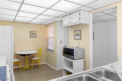 Kitchen featuring white appliances, a drop ceiling, white cabinets, light countertops, and light tile patterned floors