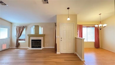 Unfurnished living room featuring light wood-style flooring, a tile fireplace, and a chandelier
