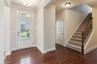 Foyer with wood finished floors, stairway, crown molding, and baseboards