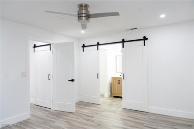 Unfurnished bedroom with a barn door, light wood-s