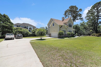 View of home's exterior with driveway, a chimney, an attached garage, a lawn, and brick siding