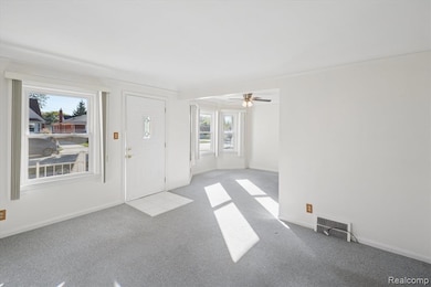Foyer with carpet floors and a ceiling fan