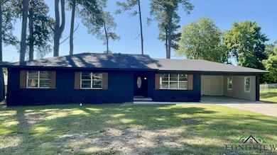 Ranch-style home featuring concrete driveway, an attached carport, a front yard, and crawl space