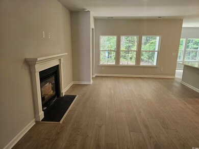 Unfurnished living room featuring dark wood-style flooring, a glass covered fireplace, and baseboards