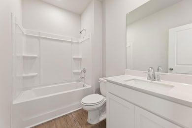 Full bathroom with washtub / shower combination, vanity, toilet, and wood finished floors