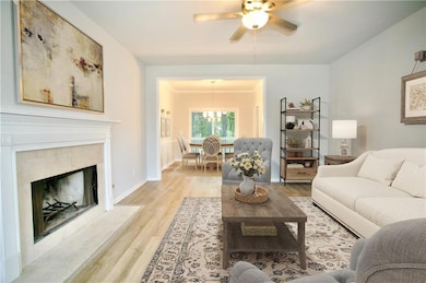 Living area with  fireplace, wood finished floors, and ceiling fan