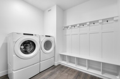 Washroom with dark wood-style floors and washing machine and clothes dryer