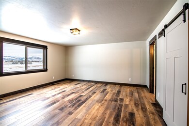 Empty room featuring a barn door, a mountain view, wood-type flooring, and a textured ceiling