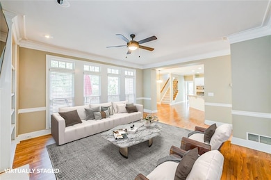 Living area with stairs, a ceiling fan, light wood