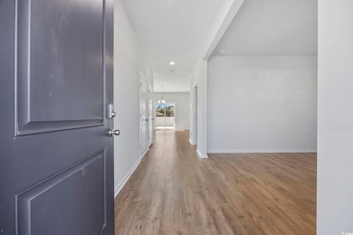 Hallway with light wood-style floors, a chandelier, and recessed lighting