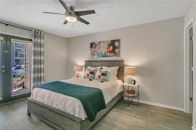 Bedroom with a textured ceiling, hardwood / wood-style flooring, and ceiling fan