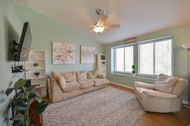 Living room with wood finished floors, vaulted ceiling, and ceiling fan