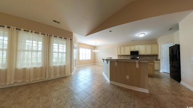 Kitchen featuring freestanding refrigerator, stainless steel microwave, lofted ceiling, a breakfast bar, and decorative backsplash