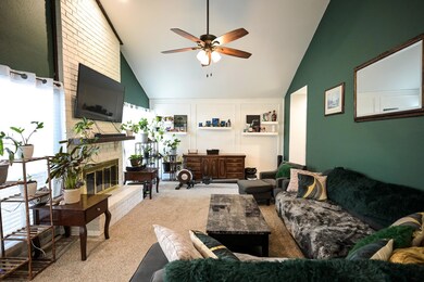 Carpeted living room with brick wall, a fireplace,