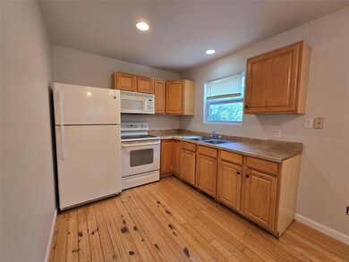 Kitchen with white appliances, light wood-style f