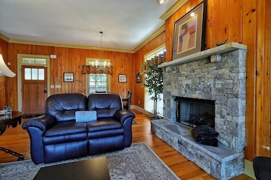 Living area featuring wood walls, wood finished floors, a fireplace, crown molding, and a chandelier