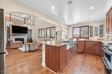 Kitchen featuring brown cabinetry, light stone counters, a kitchen breakfast bar, and recessed lighting