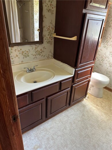 Bathroom featuring vanity, toilet, and a shower