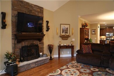The beautiful great room with stone fireplace and high ceilings, lots of trim, and beautiful solid hardwood floors