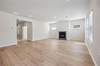 Unfurnished living room featuring a fireplace with flush hearth, light wood-type flooring, and recessed lighting