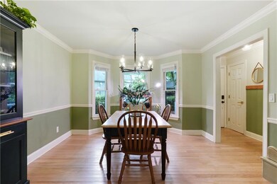 Dining area featuring light wood finished floors, a chandelier, crown molding, and baseboards