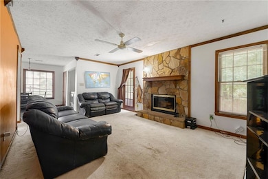 Living area with ceiling fan, ornamental molding, carpet floors, a fireplace, and baseboards