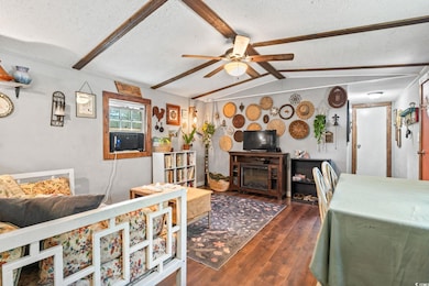 Living room with a textured ceiling, a ceiling fan, wood finished floors, cooling unit, and a fireplace